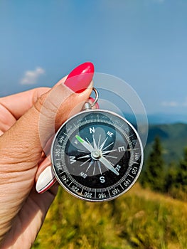 Girl holding a compass in a hand on the carpathian mountains background