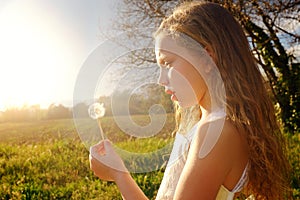 Girl holding dandelion at sunset.