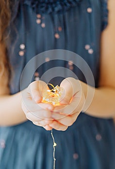 girl holding decorative garland palms warm light