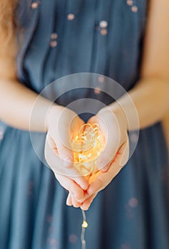 girl holding decorative garland palms warm light