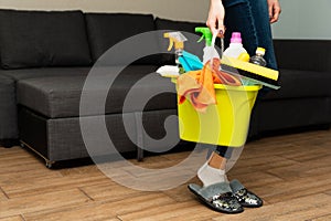 A girl is holding detergents in a bucket on the background. Woman is ready to clean house. Cleaning in a house. Clean and wash photo