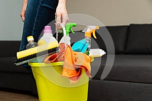 A girl is holding detergents in a bucket on the background. Woman is ready to clean house. Cleaning in a house. Clean photo