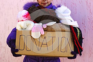 Girl holding donation box with winter clothes