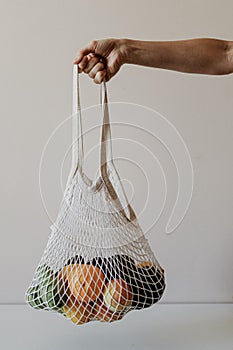 The girl is holding an eco-aware handbag full of fruits.