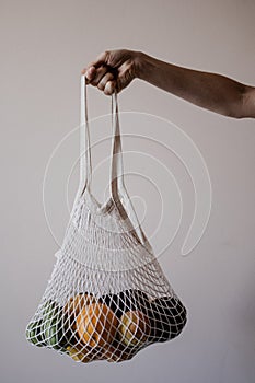 The girl is holding an eco-aware handbag full of fruits.