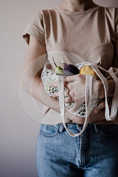 The girl is holding an eco-aware handbag full of fruits.