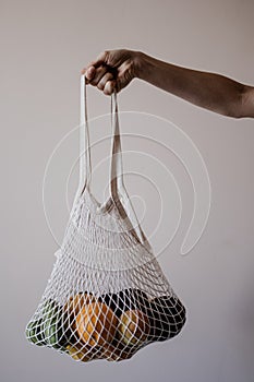 The girl is holding an eco-aware handbag full of fruits.