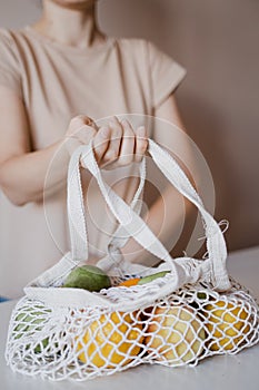 The girl is holding an eco-aware handbag with a variety of fruits.