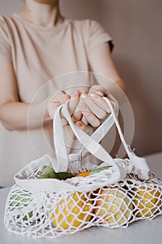 The girl is holding an eco-aware handbag with a variety of fruits.