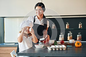 Girl is holding eggs. Mother with her daughter are preparing food on the kitchen