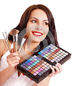 Girl holding eyeshadow and makeup brush.