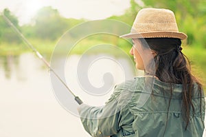 Girl holding a fishing rod, fishing on a lake.