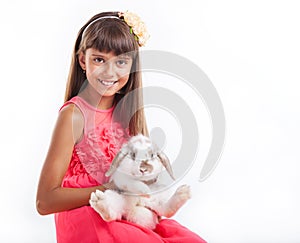 Girl holding flap-eared rabbit against white