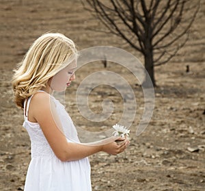 Girl holding flower in baren landscape