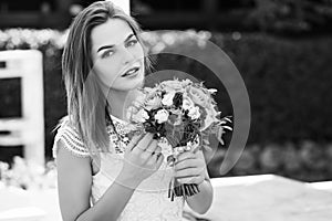 Girl holding flowers in hands, young beautiful bride in white dress holding wedding bouquet, bouquet of bride from rose cream