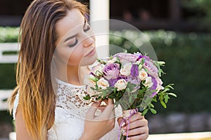 Girl holding flowers in hands, young beautiful bride in white dress holding wedding bouquet, bouquet of bride from rose cream spra