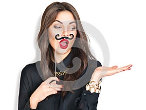 Girl holding funny mustache on stick and showing empty copyspace