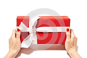 Girl holding a gift, female hands, red gift box with red ribbon