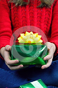 Girl holding a gift with a yellow ribbon, maybe a Christmas package.