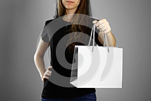 Girl holding a gray paper gift bag. Close up. Isolated background