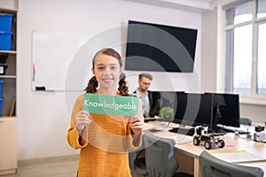 Girl holding green sign with word knowledgeable