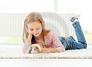 Girl holding guinea pig on the floor