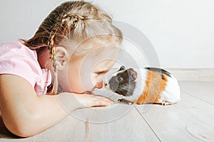 A girl holding a guinea pig in her arms, on a black background. a lot of joy and fun