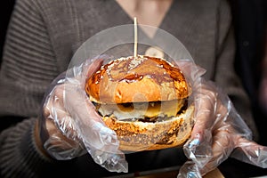 Girl holding a hamburger in her hands and getting ready to eat it. Close-up, selective focus