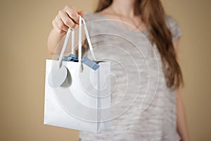 Girl holding in hand blank blue paper gift bag mock up. Empty pa