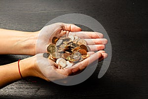 Girl holding a handful of coins in her hands on a black background