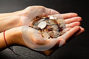 Girl holding a handful of coins in her hands on a black table background