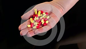 Girl holding a handful of pills in hand, close-up.