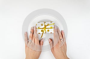 Girl holding in hands small gift box and untying a ribbon on white background.Flatly, top view. Copy space mockup