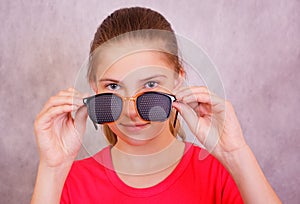 Girl holding in the hands of the training glasses for vision correction