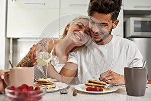 Girl holding head on man shoulder during breakfast