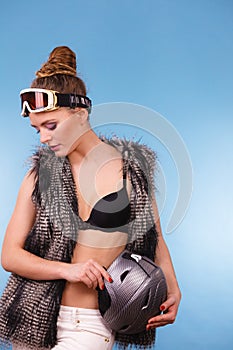 Girl is holding helmet and wearing goggle.