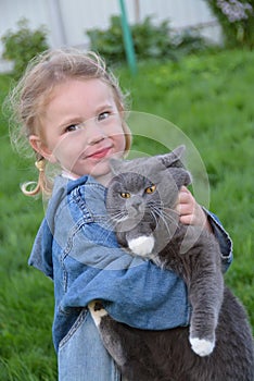 The girl is holding her beloved pet cat in her arms.