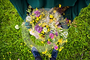 Girl holding in her hand a beautiful bouquet with multi-colored wild flowers. Amazing bunch of wilf flowers in the nature