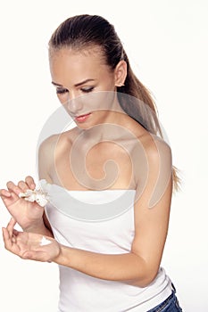 Girl holding in her hand a white lily and cream in the other.