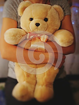 A girl is holding and hugging a teddy bear. Concept idea - goodbye to childhood. Vintage style