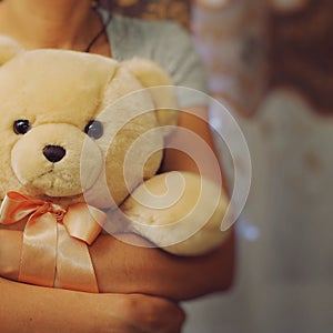 A girl is holding and hugging a teddy bear. Concept idea - goodbye to childhood. Vintage style. Place for your text