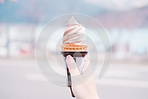 A girl holding ice cream cone held up to the hot summer sky with