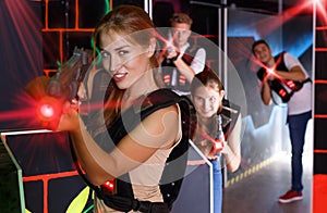 Girl holding laser pistol while playing lasertag game with frien