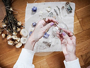 A girl is holding a little glass jar  on her altar in lavender tones