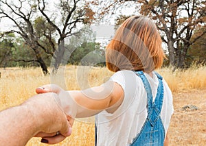 Girl Holding Man Hand in Brown Field