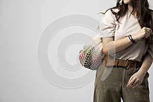 Girl is holding mesh shopping bag with vegetables, greens without plastic bags. Zero waste, plastic free. Eco friendly