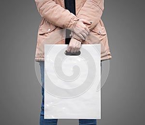 The girl is holding a mockup white plastic bag. A girl with a package on isolated background