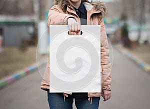 The girl is holding a mockup white plastic bag. A girl with a package on the street in the park