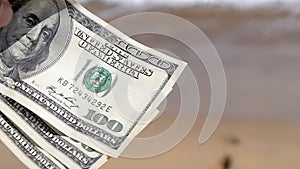 Girl holding money bill of 300 dollars on background of sea ocean