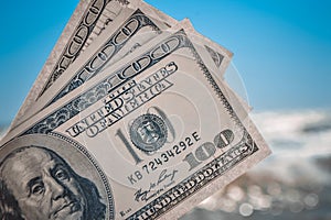 Girl holding money bill of 300 dollars on background of sea ocean